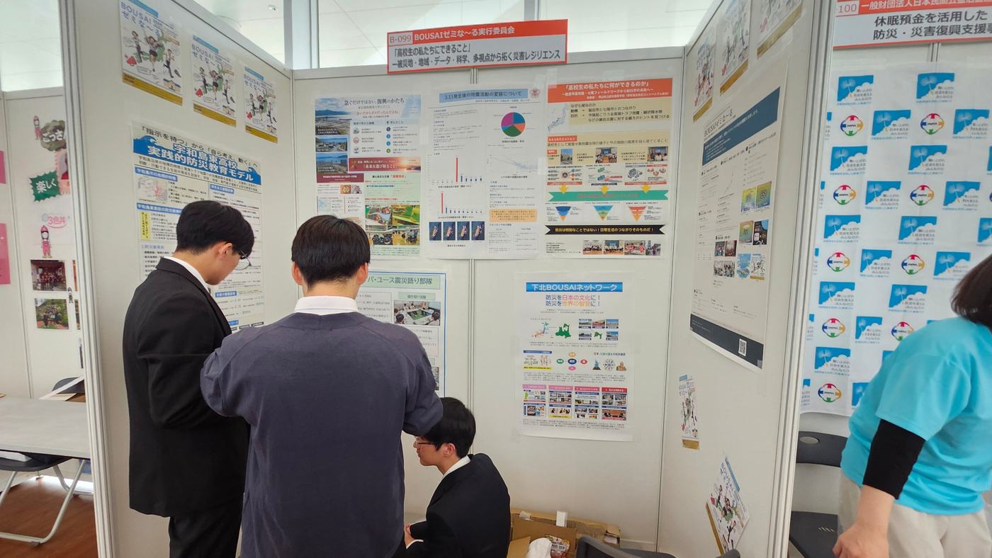 B-099ブースのパネル展示を見る来場者